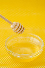 A spoon for honey in a plate with honey on a yellow background