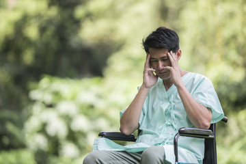 Alone young disabled man in wheelchair at the garden