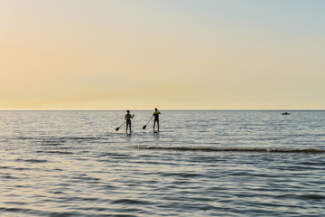 jeune couple en stand up face au soleil couchant