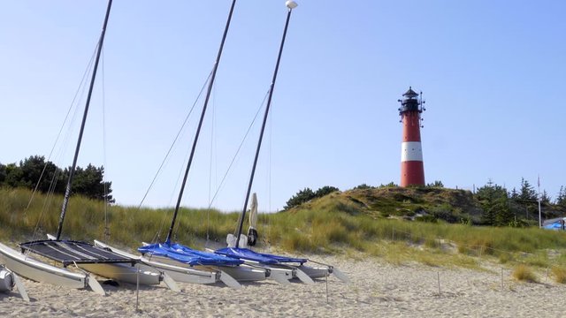 Leuchtturm H&ouml;rnum Sylt mit D&uuml;nen Landschaft und Surfschule  am Strand
