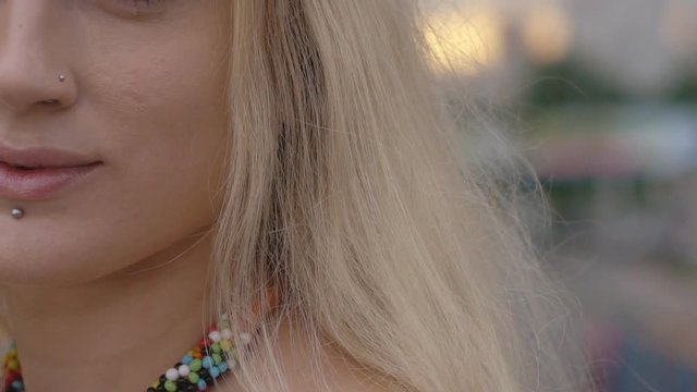 young nice blonde girl is walking along the highway. A hippie woman with piercings in her face. Attractive woman with a punctured lip and nose HD slowmotion