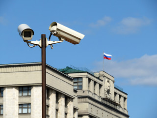 White security cameras against the parliament building of Russia with russian flag. Big brother...