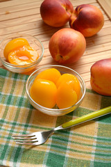 peaches in syrup in the glass bowl with fruit around