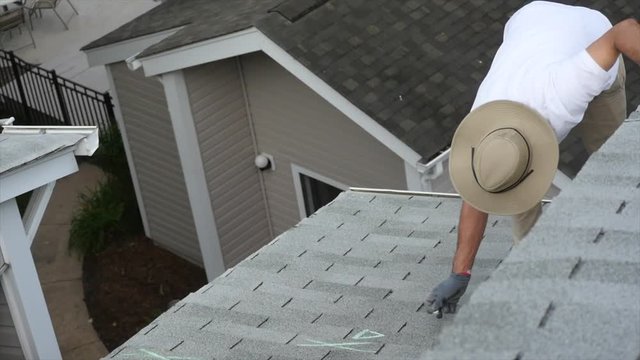 Single inspector from above, chalking a roof for damage at the edge of the roof.  You can see several buildings and the complexity makes for an interesting view.