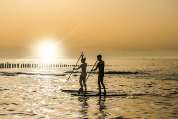 jeune couple en stand up face au soleil couchant