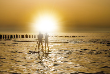 jeune couple en stand up face au soleil couchant