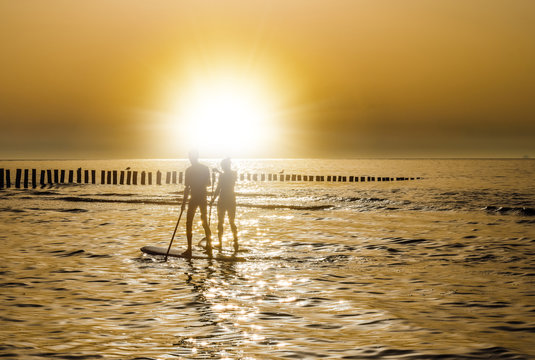 jeune couple en stand up face au soleil couchant