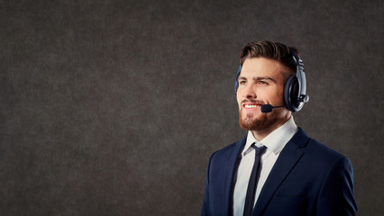 A male call center operator with headset on gray background.