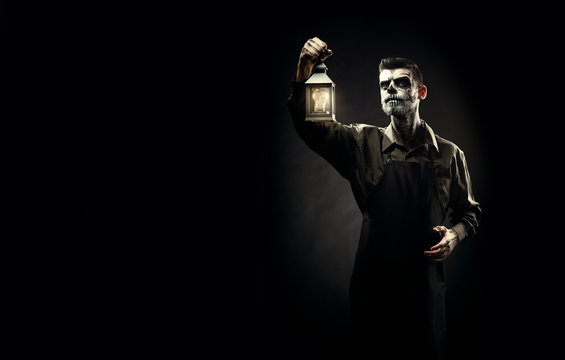 Portrait of man with Halloween skull makeup on the black background.