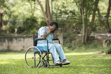 Lonely elderly woman sitting sad feeling on wheelchair at garden in hospital