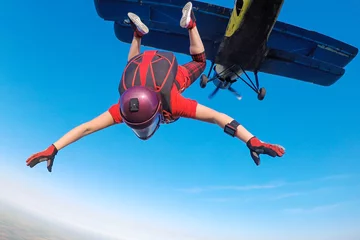 Afwasbaar Fotobehang Luchtsport Skydiver in het rood die uit het vliegtuig springt