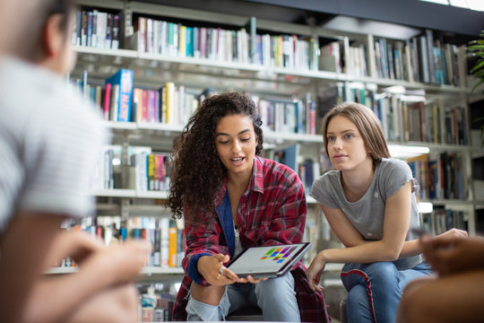 High school students studying together in a library with a digital tablet - Powered by Adobe