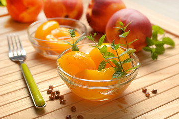 peaches in syrup in the glass bowl with fruit around