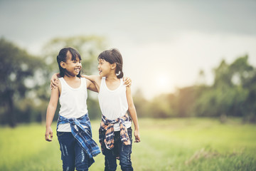 Two little girls hand holding together having fun in the park