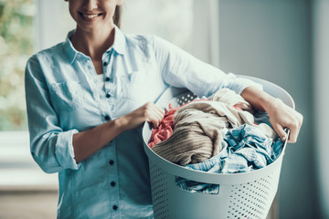 Young Smiling Woman holds Basket of Clean Clothes