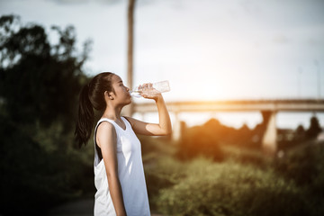 Beautiful young fitness woman drinking water after running exercise