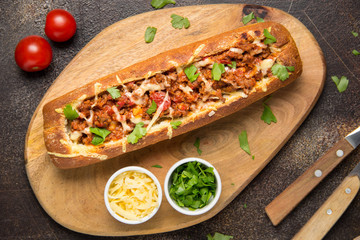 Baguette stuffed with bolognese ragout of minced beef, tomatoes and cheese. A delicious Italian lunch, tasty snacks, homemade sandwich
