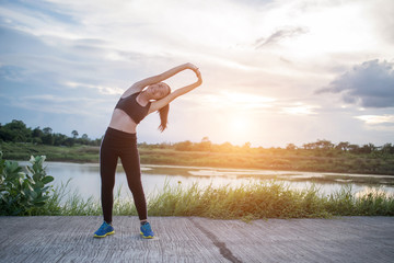 Healthy young woman warming up outdoors workout before training session at the park.