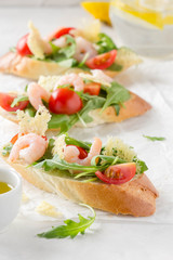 Bruschetta with arugula, shrimp, cherry tomatoes and balsamic vinegar. Three  tasty open sandwiches for lunch