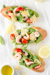 Bruschetta with arugula, shrimp, cherry tomatoes and balsamic vinegar. Three  tasty open sandwiches for lunch