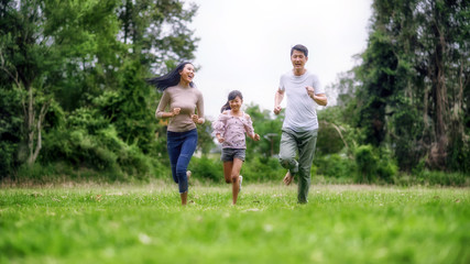Obraz premium Happy family of three people, mother, father and child in green garden; Asian family are happy working in the parks; Enjoying family time together in the meadow travel nature trip.