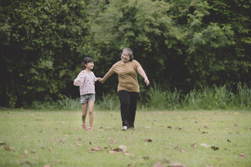 Obraz premium Grandmother and granddaughter enjoyed in the garden; a little girl kissing on the her grandmother's face.