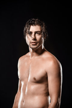 portrait of shirtless man with wet hair looking at camera isolated on black