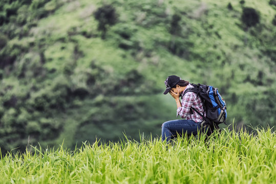 Asian young woman backpack  waiting for help  in the nature rice farmhouse. , her is feeling sorry and have hopefully someone will help her; travel concept.