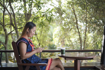 Naklejka premium Portrait of beautiful asian girl using her mobile phone in cafe.