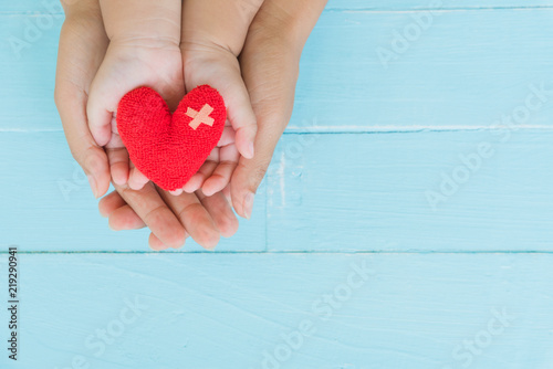Top view of adult and child holding red heart in hands, Happy family relationships, Valentine's day, Mother's Day, Love and health care concept.