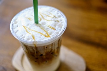 In the cafe, iced coffee with ice cubes in a cup on wooden background