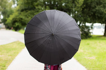 circle shape of open classic black umbrella with sheep introvert human behind it and blurred...