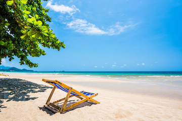 Tropical tree and beach chair at white sand beach and blue sea