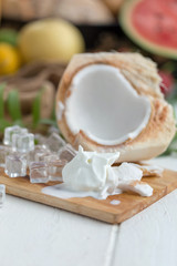 Fototapeta na wymiar Coconut Milk Ice Cream and Young Coconut on a wooden plate with ice cubes and fruit as background