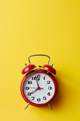 Red vintage alarm clock on yellow background. Alarm clock with place for text.