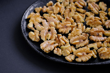 Roasted walnut kernels are on the black pan,
