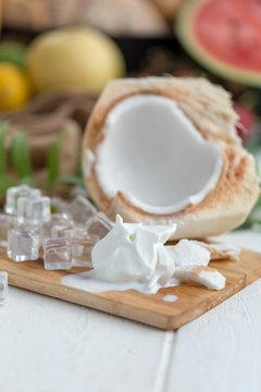 Coconut Milk Ice Cream and Young Coconut on a wooden plate with ice cubes and fruit as background