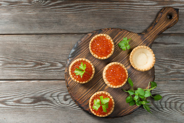 Red caviar in tartlets on a wooden table