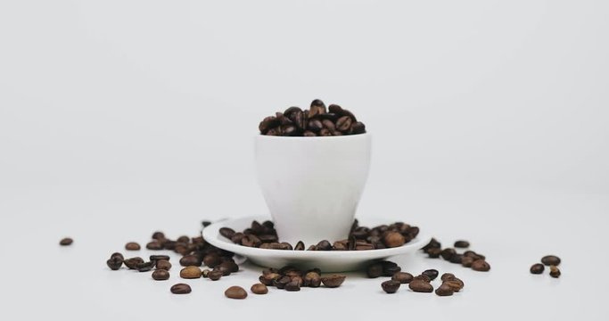 White ceramic coffee cup full of coffee beans and saucer