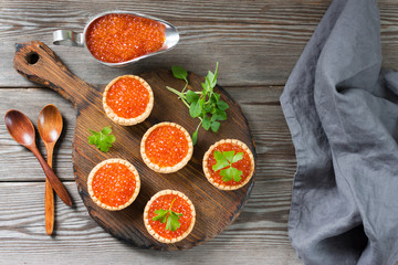 Red caviar in tartlets on a wooden table