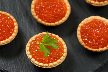 Red caviar in tartlets on a black background