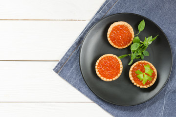 Red caviar in tartlets on a white board