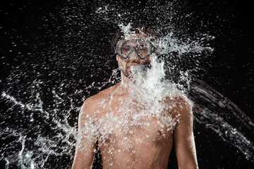 portrait of shirtless man in swimming mask with snorkel swilled with water splash isolated on black