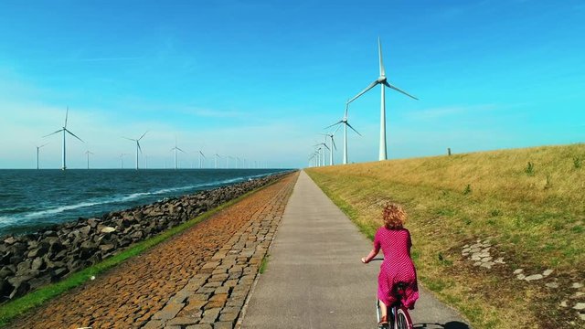 Girl cycling along wind turbines