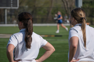 Two female head coaches stand on sidelines calling instructions to girl soccer players in...