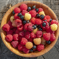 Pile of Fresh Raspberries in the Bowl on a wooden background.