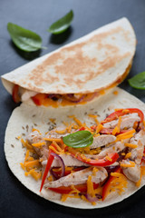 Close-up of tortilla bread with roasted chicken, vegetables and cheddar for making quesadilla, selective focus