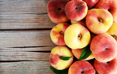 Fresh organic chinese flat peaches with leaves on old wooden background.Saturn donut, Doughnut...