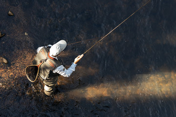 Fly fisherman using flyfishing rod - Powered by Adobe