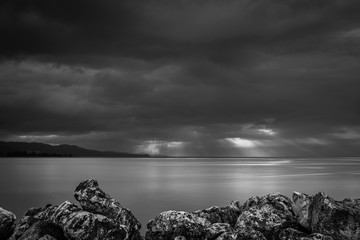 Dramatic black and white view of sun rays through the clouds from the coastline in Montego Bay,...